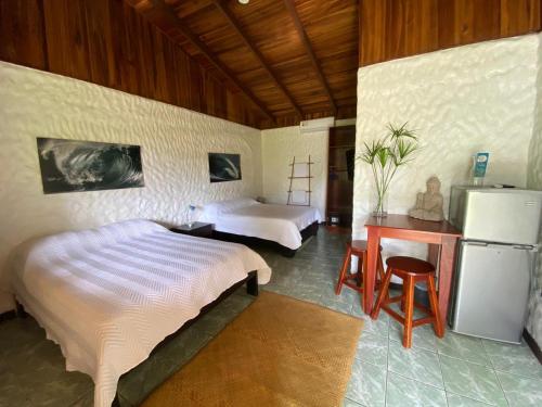 a bedroom with two beds and a desk and a refrigerator at Vida Hermosa in Playa Hermosa