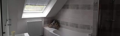 ein Bad mit einer Badewanne und einem Fenster in der Unterkunft COTE MER CHEMINEE 400 m de la plage 4 vélos in Bénodet