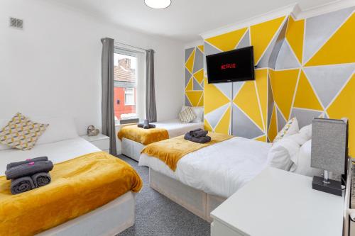 a bedroom with two beds and a tv on the wall at The World Famous Henderson House FREE PARKING in Liverpool