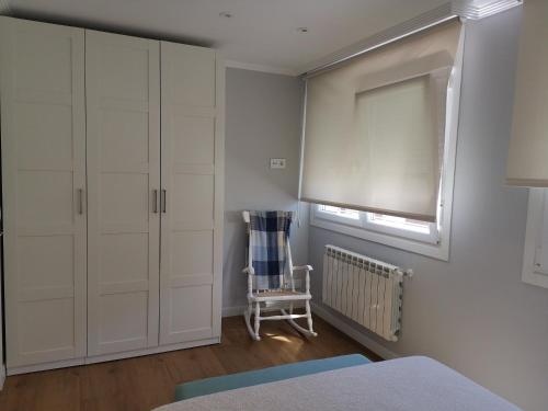 a bedroom with white cabinets and a window and a chair at Apt Moderno céntrico y soleado in Pontevedra