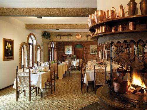 a restaurant with tables and chairs and a fireplace at Locanda al Castello Wellness Resort in Cividale del Friuli