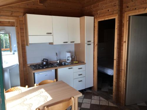 a small kitchen with white cabinets and a table at Chalets Tuscany Viareggio in Viareggio