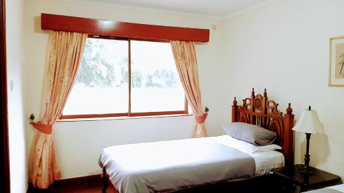 a bedroom with a bed and a large window at Kwezi Cottage at The Great Rift Valley Lodge & Golf Resort Naivasha in Naivasha