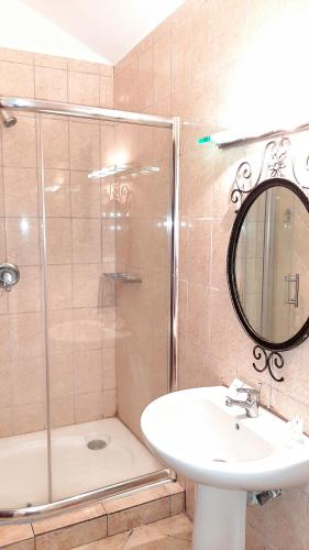 a bathroom with a sink and a shower with a mirror at Kwezi Cottage at The Great Rift Valley Lodge & Golf Resort Naivasha in Naivasha