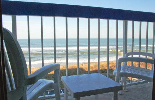 two chairs and a table on a balcony overlooking the beach at Holiday Inn Express Nags Head Oceanfront by IHG in Nags Head