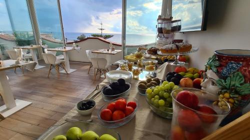 a table with bowls of fruit on it with a view of the ocean at Pantanello Rooms Avola in Avola