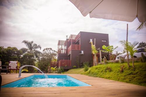 una piscina con sombrilla junto a una casa en Reserva Brasileira, en Praia do Rosa