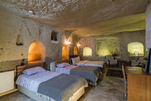 a room with three beds in a stone room at Atilla's Cave Hotel in Nevsehir