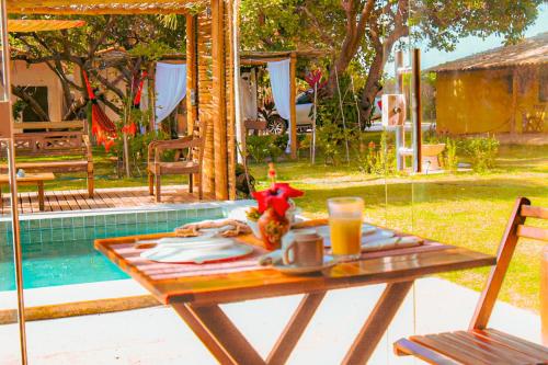 a picnic table with a drink on it next to a pool at Pousada Quinta da Lagoa Azul in Jijoca de Jericoacoara