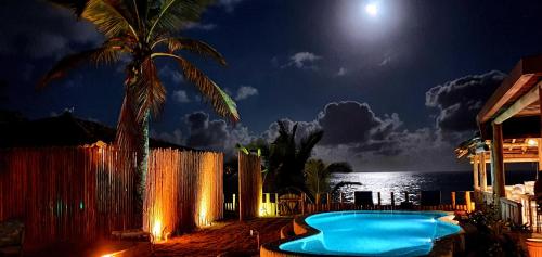 a swimming pool at night with a full moon at Pousada San Antonio Praia in Caraíva