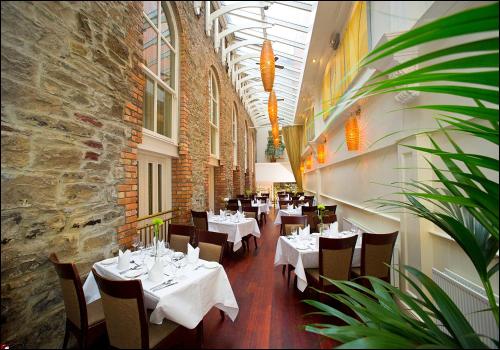 ein Restaurant mit weißen Tischen und Stühlen und einer Ziegelwand in der Unterkunft Westenra Arms Hotel in Monaghan