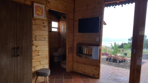 a room with a tv and a fireplace in a log cabin at Altozano Cabañas in Guatavita