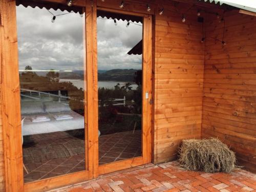 a sliding glass door of a wooden house with a view at Altozano Cabañas in Guatavita