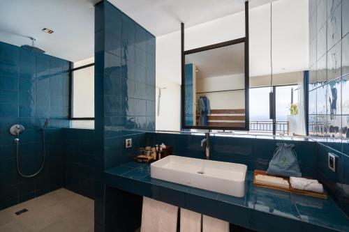 a blue bathroom with a sink and a shower at Adiwana Warnakali Resort in Nusa Penida