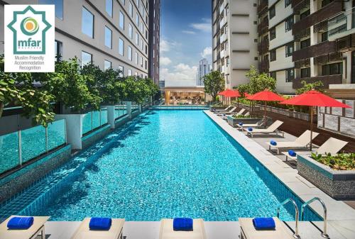 a swimming pool with chairs and umbrellas on a building at Amari Johor Bahru in Johor Bahru