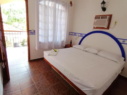 1 dormitorio con 1 cama blanca con marco azul en Don Luis Hostal - Sucursal Galeana - Tecolutla, en Tecolutla