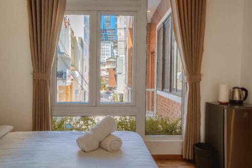 a bedroom with a large window with towels on a bed at The Green House Da Lat in Da Lat