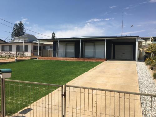 a house with a fence in front of a yard at Family Tides in Wallaroo
