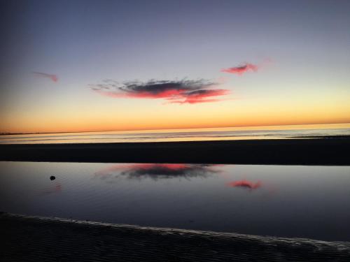 a sunset on the beach with a reflection in the water at Family Tides in Wallaroo