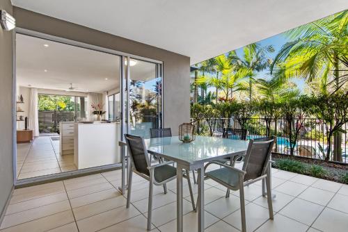 a kitchen and dining room with a glass table and chairs at Metzo Noosa Resort in Noosaville