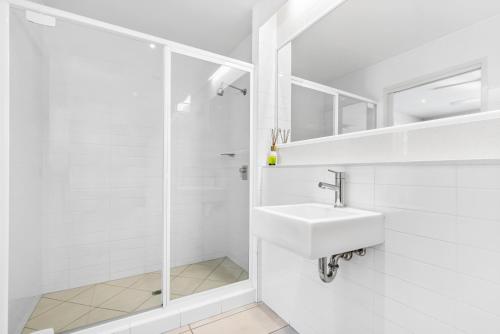 a white bathroom with a sink and a shower at Metzo Noosa Resort in Noosaville