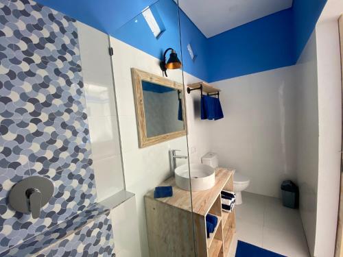 Kura Kura Divers Lodge في آميد: حمام بجدران زرقاء وبيضاء ومغسلة