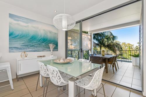 a dining room with a glass table and white chairs at Metzo Noosa Resort in Noosaville