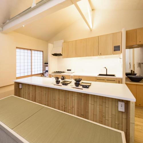 a large kitchen with white counter tops and wooden cabinets at Yuigahama 千世 in Kamakura