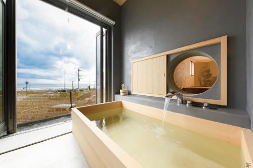 a bathroom with a tub with a mirror and a window at Yuigahama 千世 in Kamakura