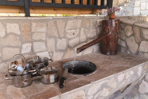 デヴィンにあるPlaninski Polah Houseの石造りのカウンターに鍋やフライパンが入ったキッチンシンク