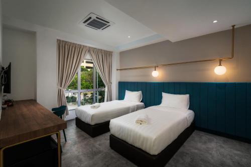a hotel room with two beds and a desk at Masson Hotel Butterworth in Perai