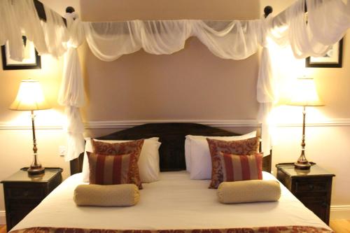 a bedroom with a large bed with two lamps at Adare Country House in Adare