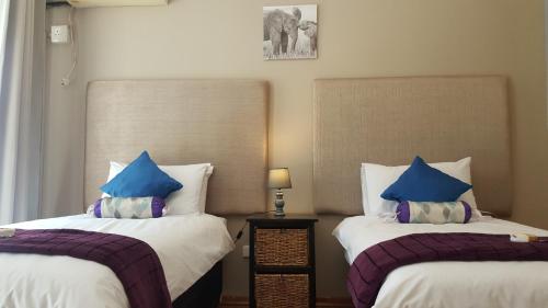 Duas camas com almofadas azuis num quarto em Luxury Heights Guesthouse em Newcastle