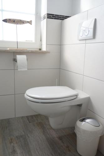 a white bathroom with a toilet and a window at Hansenhof in Kappeln