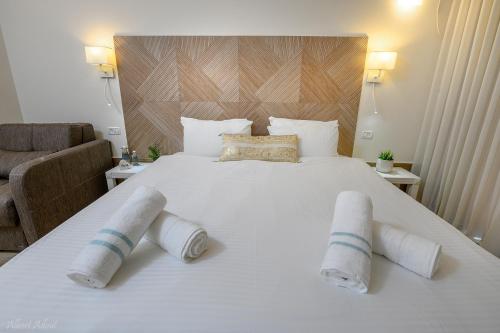 a large white bed with two rolled towels on it at Lev Hahoresh Boutique Hotel in Shomera