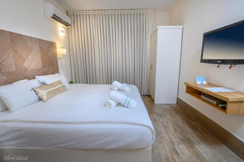 a hotel room with a large white bed and a flat screen tv at Lev Hahoresh Boutique Hotel in Shomera