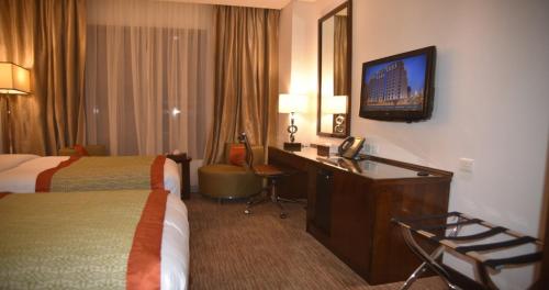a hotel room with two beds and a desk and a television at Crowne Plaza Madinah by IHG in Al Madinah