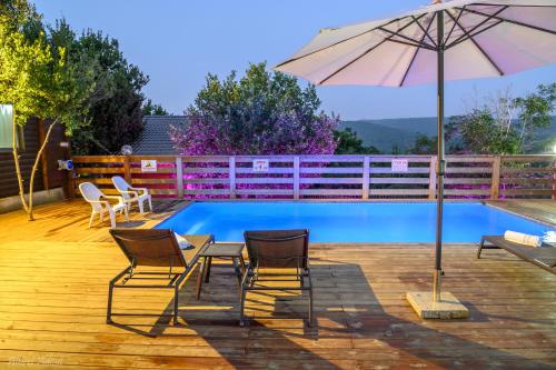 a patio with chairs and an umbrella and a pool at Lev Hahoresh Boutique Hotel in Shomera