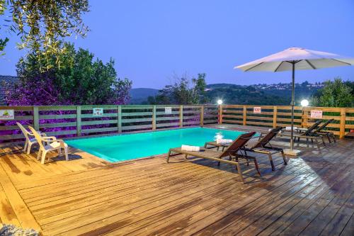 a pool with chairs and an umbrella on a wooden deck at Lev Hahoresh Boutique Hotel in Shomera