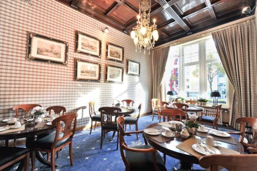 a restaurant with wooden tables and chairs and a chandelier at Hotel Windsor in Düsseldorf