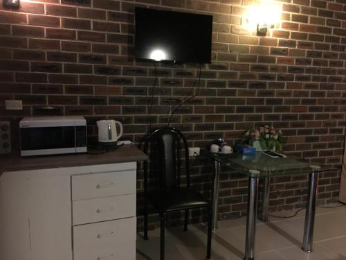a kitchen with a table and a tv on a brick wall at Motel Studio room in Somersby