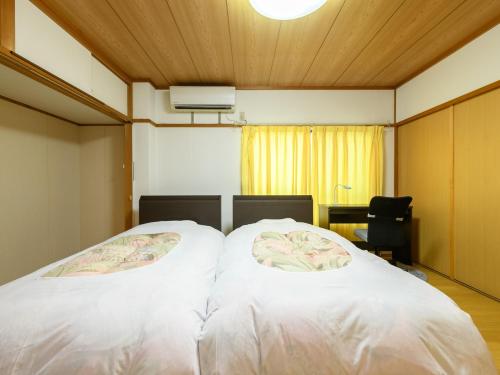 a bedroom with a bed with white sheets and a desk at Tabist Sakipo Minamichita in Morozaki