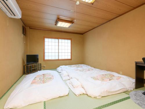 a room with three beds in it with a tv at Tabist Sakipo Minamichita in Morozaki