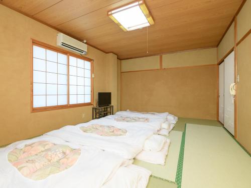 a room with four beds in it with a window at Tabist Sakipo Minamichita in Morozaki