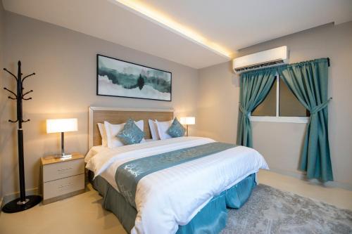 a bedroom with a large bed with blue curtains at شقق قصر السفير in Riyadh