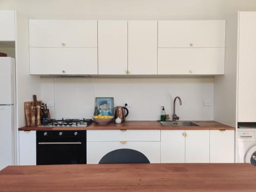 a kitchen with white cabinets and a sink and a stove at Kia Noho in Havelock North