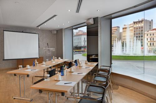 a conference room with tables and chairs and a projection screen at Athens Tiare by Mage Hotels in Athens