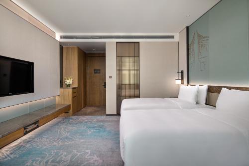a hotel room with two beds and a flat screen tv at C&D Hotel,Xiamen Xiang'an-Late Check Out & Free Welcome Snacks in Xiamen