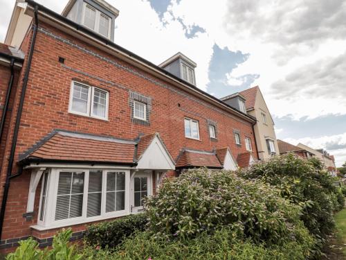a red brick house with white windows and bushes at 60 Galley Hill View in Bexhill