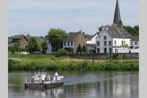 a boat floating down a river next to houses at Authentic Stays - 6p-maisonette in Eijsden